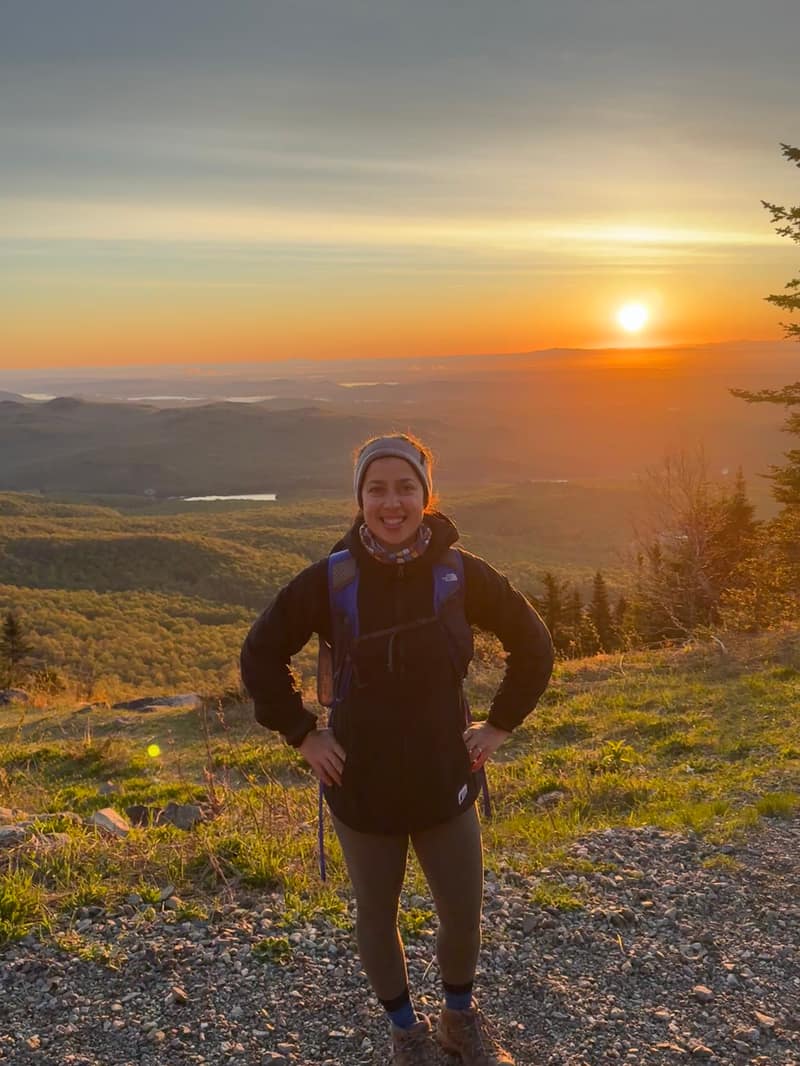 Maelle at sunrise on a mountain summit above the Québec countryside